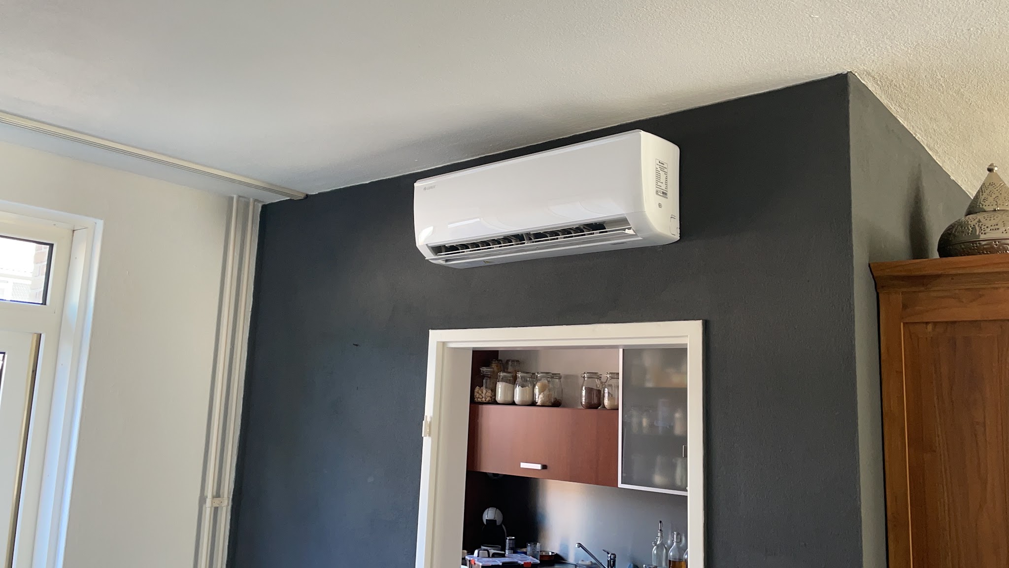 Witte binnenunit op een donkergrijze wand boven een keukendoorgang