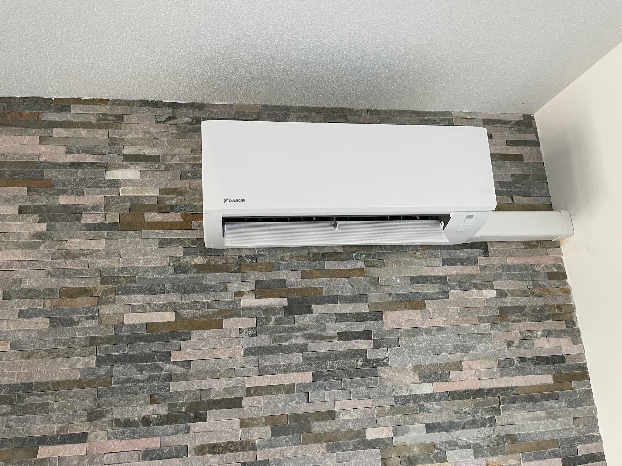 Witte Daikin binnenunit gemonteerd op een natuurstenen wand