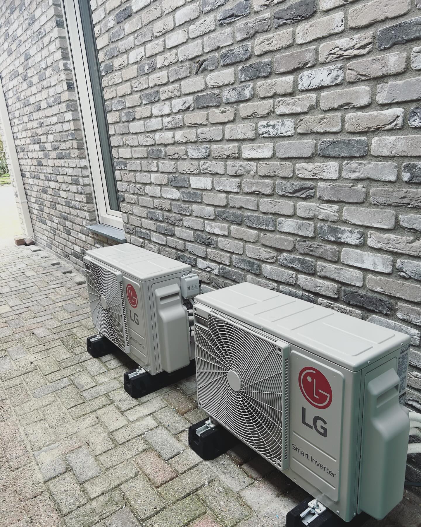 Twee LG buitenunits op de bestrating langs een gevel