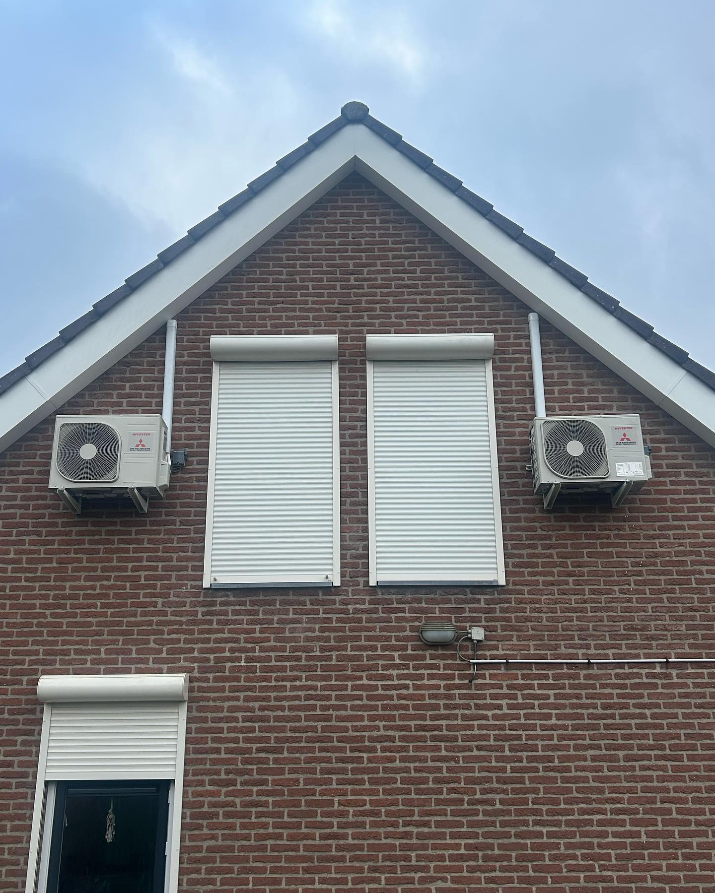 Twee Mitsubishi buitenunits symmetrisch op een bakstenen puntgevel